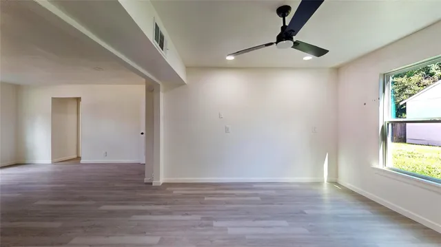 a view of an empty room with window and wooden floor