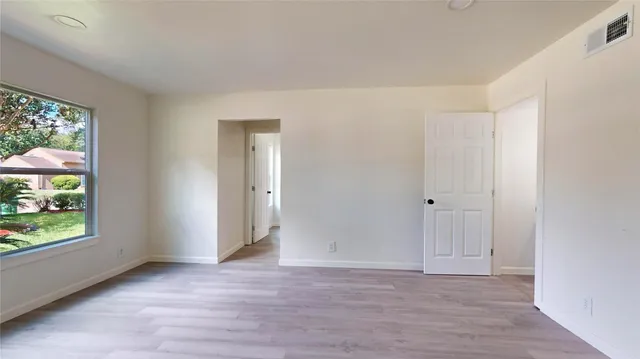 a view of an empty room with window and wooden floor