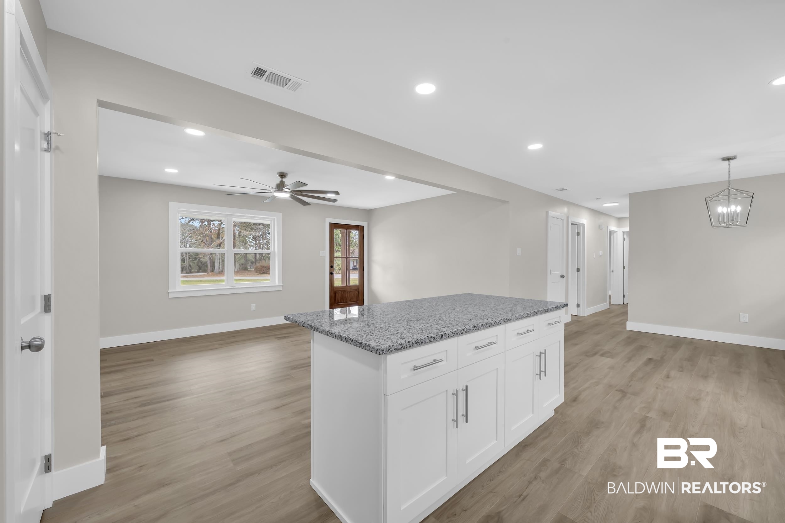 11381 Normandy Drive East Semmes, AL 36575 - Photo 23 of 23 Kitchen featuring open floor plan, light stone counters, white cabinets, light wood finished floors, and a kitchen island
