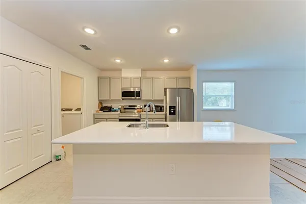 a large white kitchen with wooden floor and breakfast area