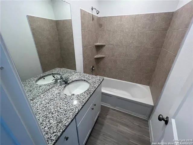 a bathroom with a granite countertop sink and a bathtub