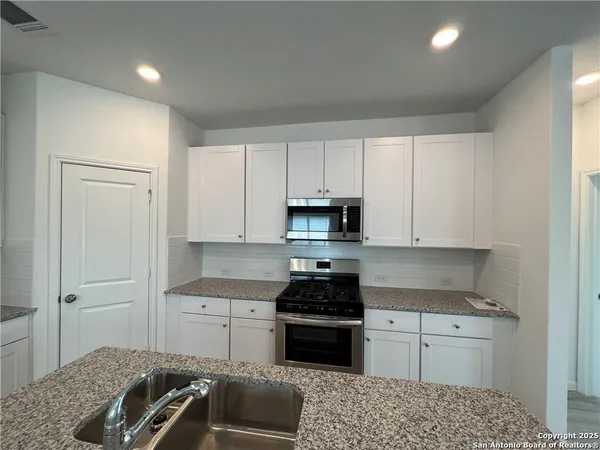 a kitchen with granite countertop a sink cabinets and stainless steel appliances