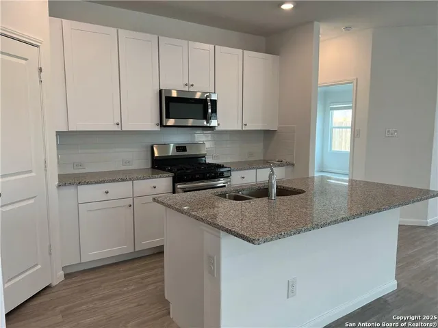 a kitchen with stainless steel appliances granite countertop a sink a stove and microwave