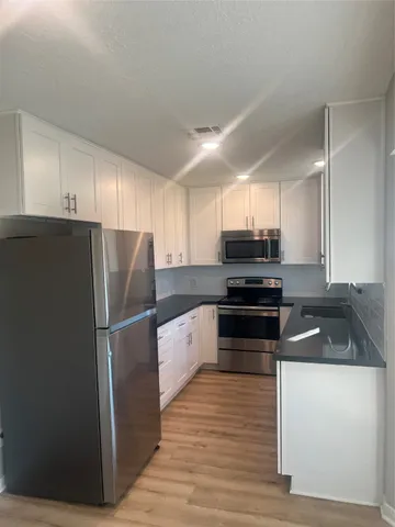 a kitchen with granite countertop a refrigerator and a stove top oven
