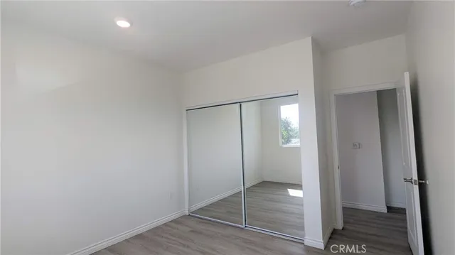 a view of an empty room with wooden floor and a bathroom