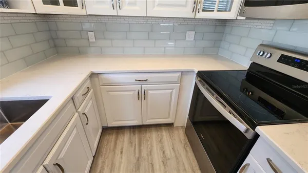 a view of a kitchen with wooden floor and cabinets