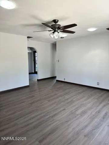 a view of an empty room with wooden floor and a ceiling fan
