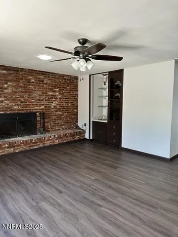 a view of a livingroom with wooden floor a ceiling fan and staircase