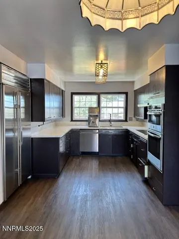 a large kitchen with a large counter top stainless steel appliances and wooden floor