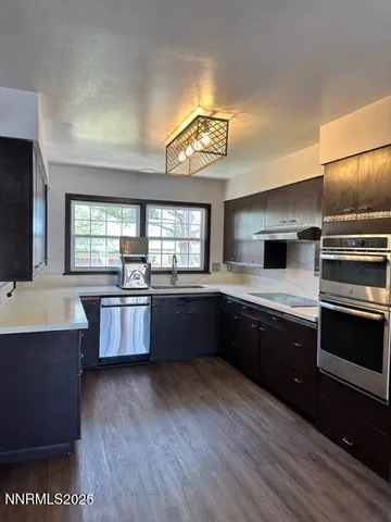 a kitchen with stainless steel appliances granite countertop a stove a sink dishwasher and a oven with white cabinets