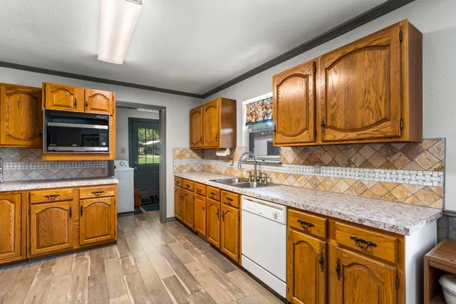 a kitchen with stainless steel appliances granite countertop wooden cabinets a sink and dishwasher a stove with wooden floor