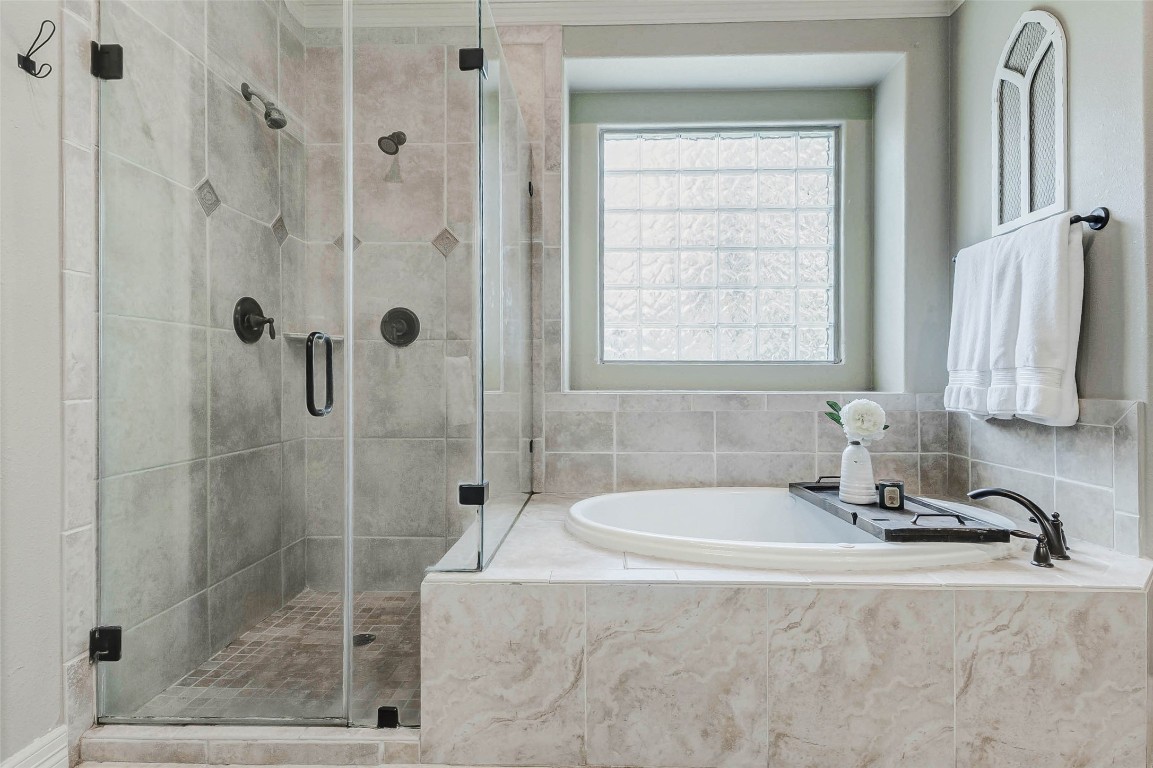 4403 Wickby Street Fulshear, TX 77441 - Photo 26 of 50 The primary ensuite features versatile bathing options, including a walk-in shower with elegant tile work and a jetted tub for ultimate relaxation. A large frosted window provides natural light while ensuring privacy.