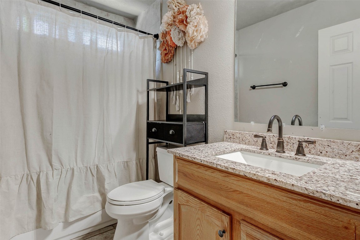 4403 Wickby Street Fulshear, TX 77441 - Photo 35 of 50 This upstairs secondary full bathroom suited for the nearby 5th bedroom features a shower/tub combo, granite countertops with a single sink, rubbed bronze fixtures, and wooden cabinetry.