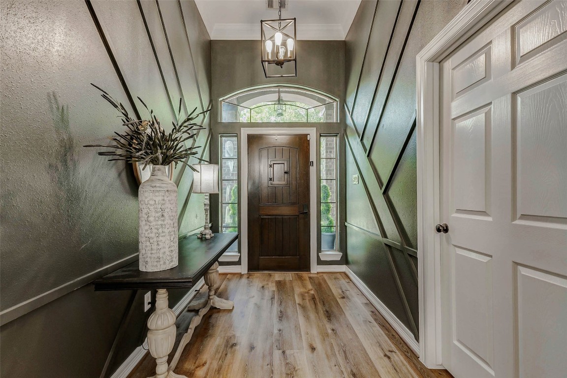 4403 Wickby Street Fulshear, TX 77441 - Photo 5 of 50 Adding a touch of sophistication, this entryway offers a modern design with tasteful LVP flooring, glass paneled windows, an elegant upgraded light fixture, and a decorative custom wood trimmed wall.