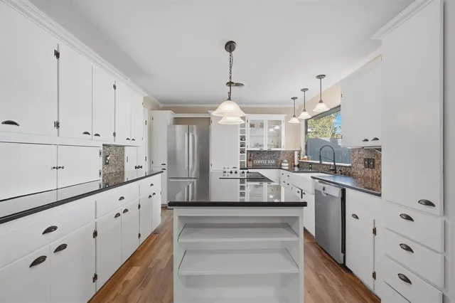 a large white kitchen with cabinets and a wooden floor
