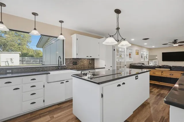 a kitchen with stainless steel appliances granite countertop a sink a stove and a wooden floor