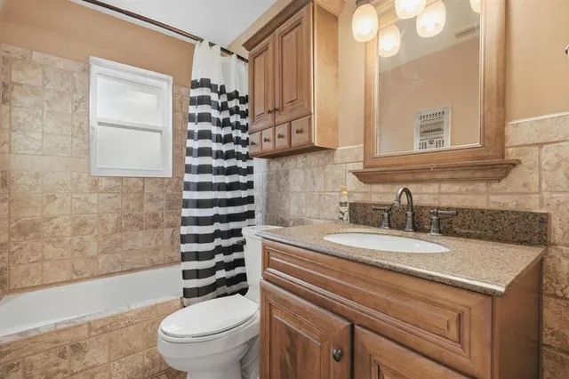 a bathroom with a granite countertop sink a toilet a mirror a vanity and shower