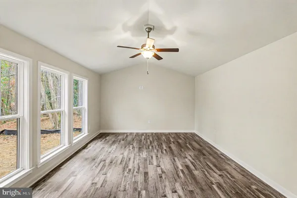a view of empty room with wooden floor and fan