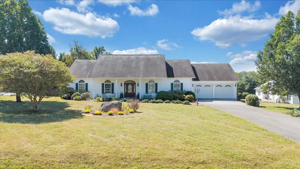 a front view of house with yard and trees in the background