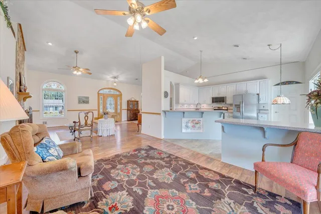 a kitchen with stainless steel appliances granite countertop a refrigerator a stove a sink dishwasher and a microwave with wooden floor