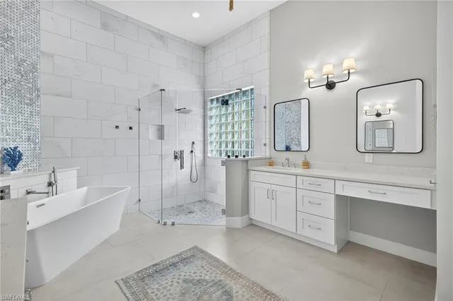 a spacious bathroom with double vanity a mirror a bathtub and shower