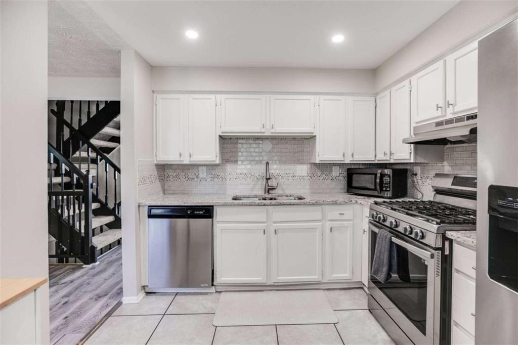 6413 Wedgewood Trace Tucker, GA 30084 - Photo 10 of 30 a kitchen with granite countertop a stove sink and cabinets