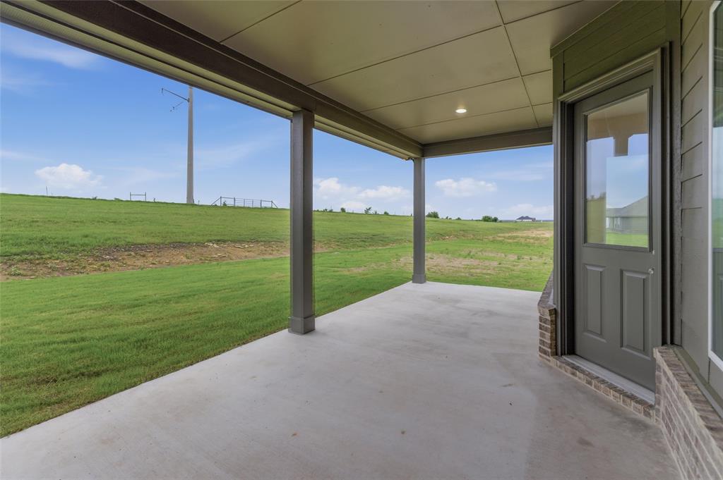 119 Hillview Trail Decatur, TX 76234 - Photo 28 of 30 Covered patio with a concrete surface, supported by dark architectural columns, featuring an exterior door with a glass pane