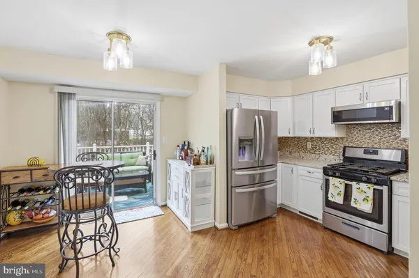 a kitchen with stainless steel appliances a dining table chairs stove and refrigerator