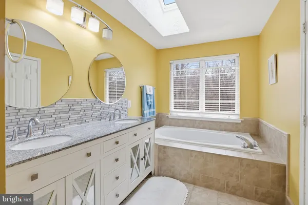 a bathroom with a granite countertop tub a sink and a large mirror