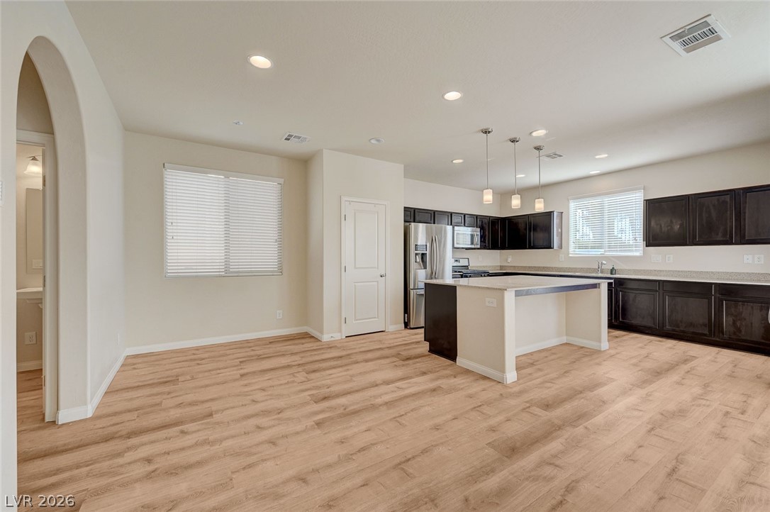 113 Elm Reed Avenue Las Vegas, NV 89113 - Photo 14 of 62 Kitchen featuring a kitchen island, stainless steel appliances, pendant lighting, light wood-style floors, and arched walkways