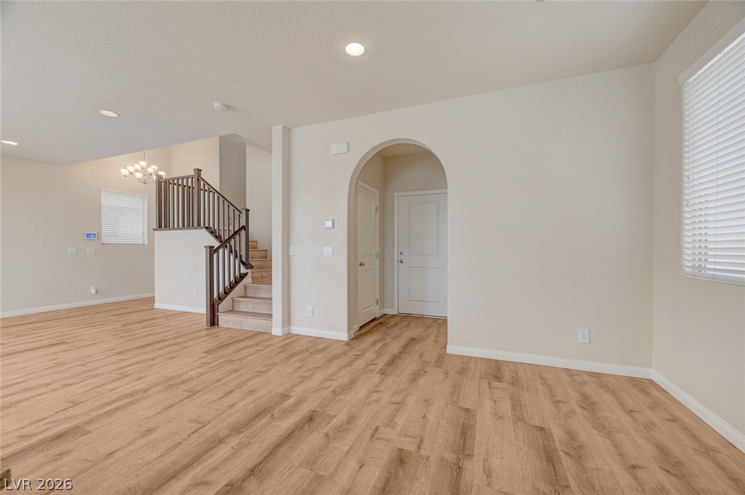 113 Elm Reed Avenue Las Vegas, NV 89113 - Photo 16 of 62 Spare room featuring arched walkways, light wood-style floors, and suspended lighting