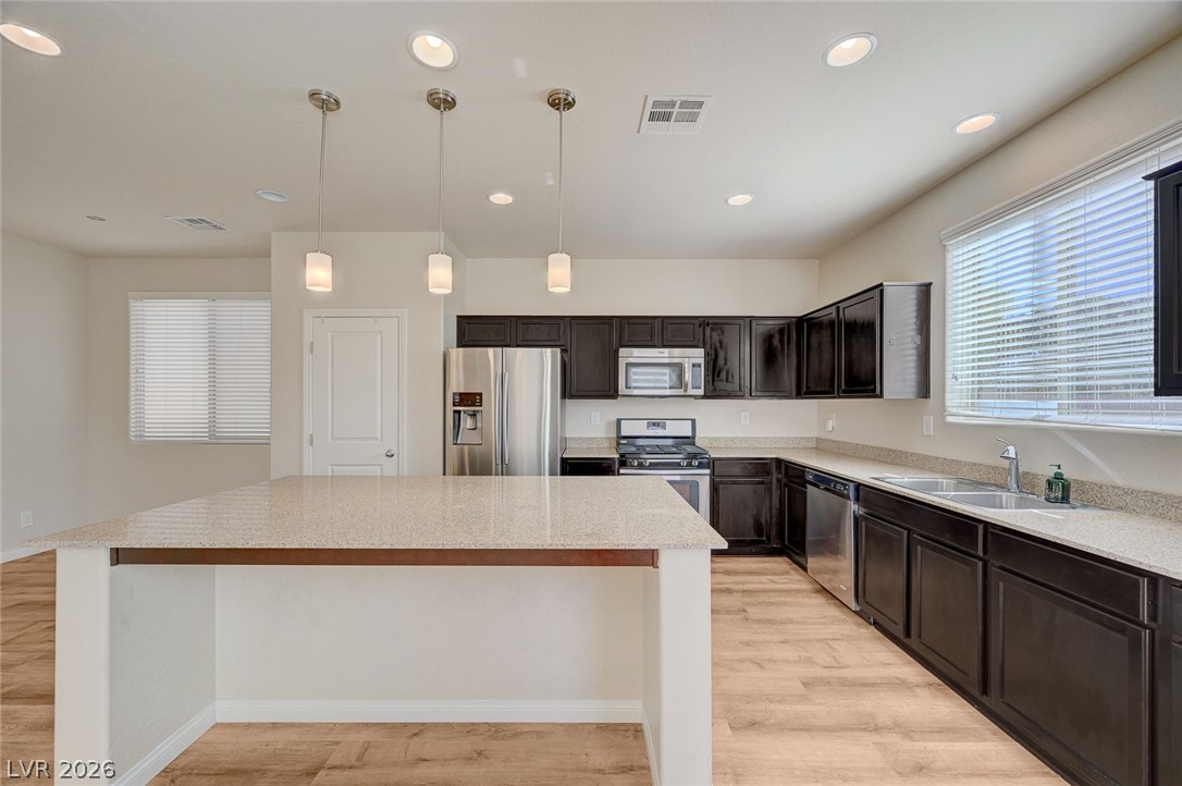 113 Elm Reed Avenue Las Vegas, NV 89113 - Photo 18 of 62 Kitchen featuring stainless steel appliances, hanging light fixtures, light wood finished floors, a center island, and dark wood finish cabinets