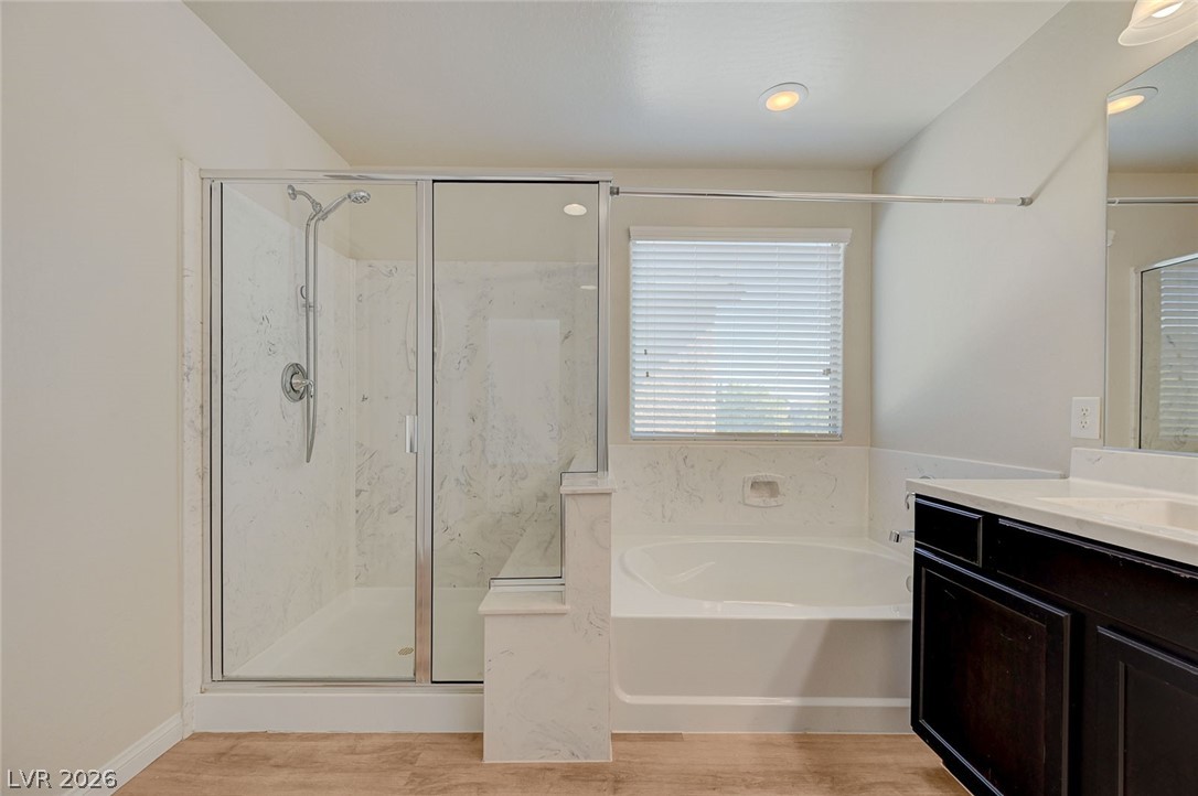 113 Elm Reed Avenue Las Vegas, NV 89113 - Photo 36 of 62 Full bathroom with a garden tub, a marble finish shower, vanity, light wood-style floors, and recessed lighting