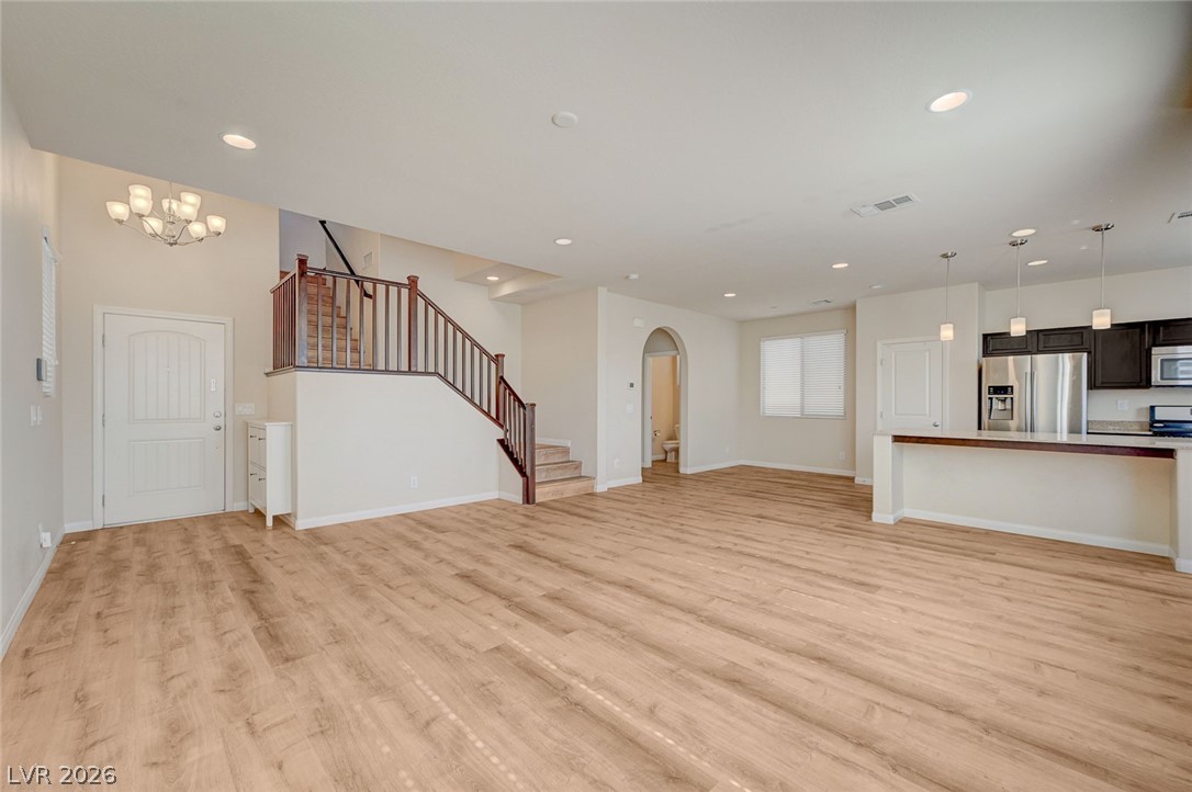 113 Elm Reed Avenue Las Vegas, NV 89113 - Photo 10 of 62 Unfurnished living room with arched walkways, light wood-type flooring, and a chandelier