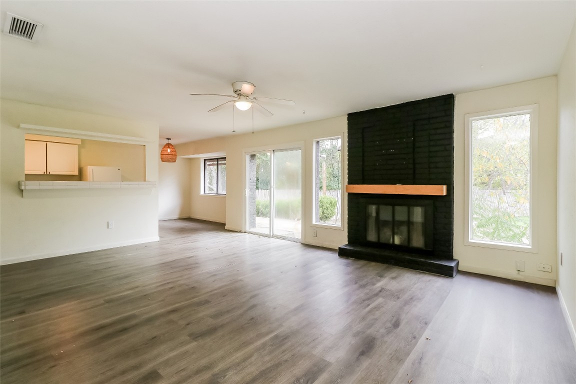 2803 Cornish Circle Austin, TX 78745 - Photo 2 of 16 Unfurnished living room with a brick fireplace, wood finished floors, and a ceiling fan