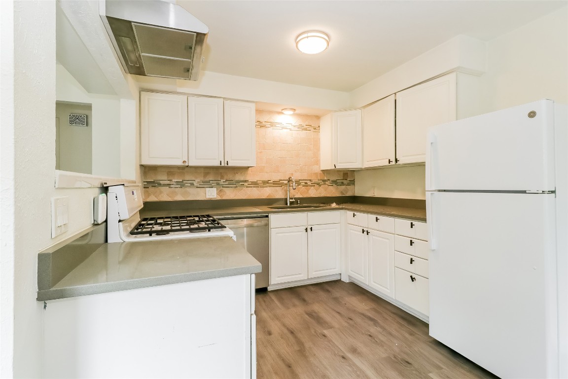 2803 Cornish Circle Austin, TX 78745 - Photo 6 of 16 Kitchen with white appliances, white cabinets, range hood, tasteful backsplash, and light wood-type flooring