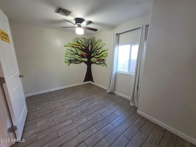 an empty room with wooden floor chandelier fan and windows