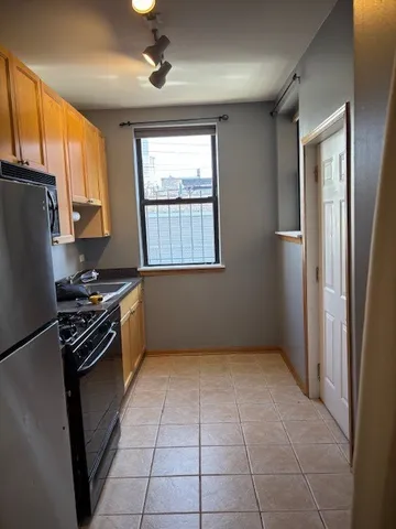 a kitchen with a refrigerator a stove top oven a sink and a window