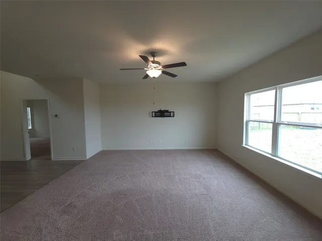 an empty room with a window and a ceiling fan