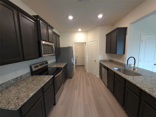 a kitchen with stainless steel appliances granite countertop a sink stove and refrigerator