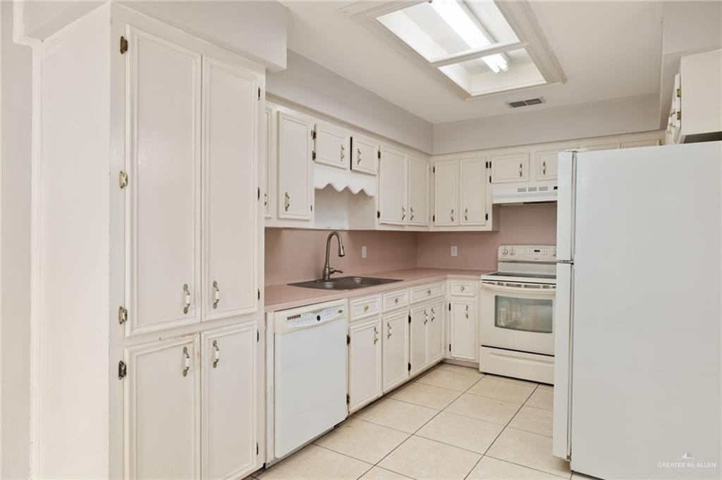 1204 East Jackson Avenue Pharr, TX 78577 - Photo 6 of 18 Kitchen featuring white appliances, light tile patterned floors, light countertops, and white cabinets