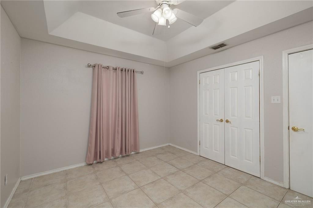 1204 East Jackson Avenue Pharr, TX 78577 - Photo 9 of 18 Unfurnished bedroom with a tray ceiling, a ceiling fan, light tile patterned floors, and a closet