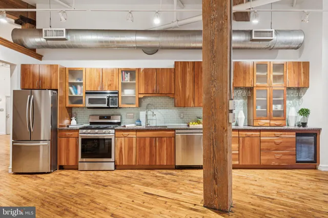 a large kitchen with stainless steel appliances granite countertop a stove and a wooden cabinets
