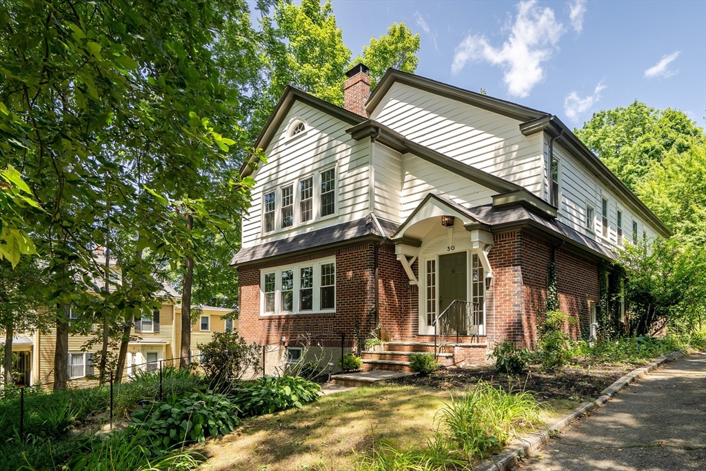 a view of house with a small yard and a large tree in it