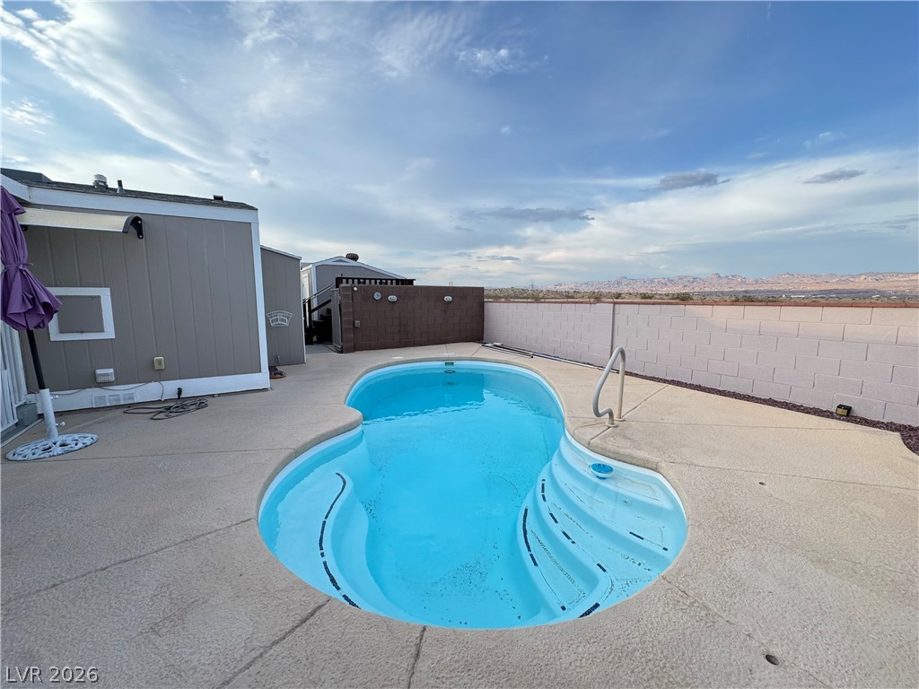3250 Del Monte Street Laughlin, NV 89029 - Photo 43 of 57 A kidney-shaped heated inground pool invites relaxation, set against a distant mountain landscape.