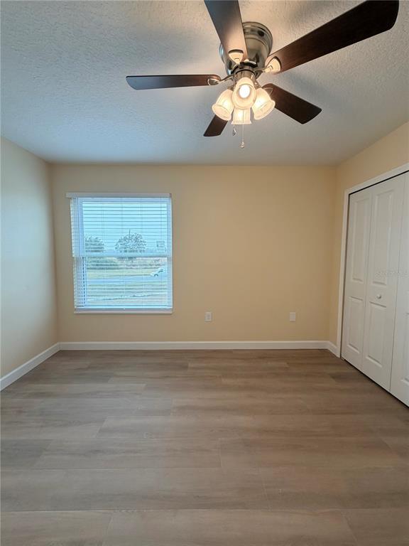 413 Britten Drive Kissimmee, FL 34758 - Photo 11 of 20 an empty room with wooden floor chandelier fan and windows