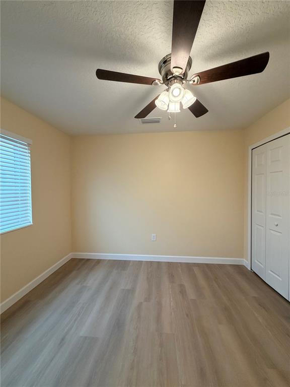 413 Britten Drive Kissimmee, FL 34758 - Photo 9 of 20 an empty room with wooden floor fan and windows