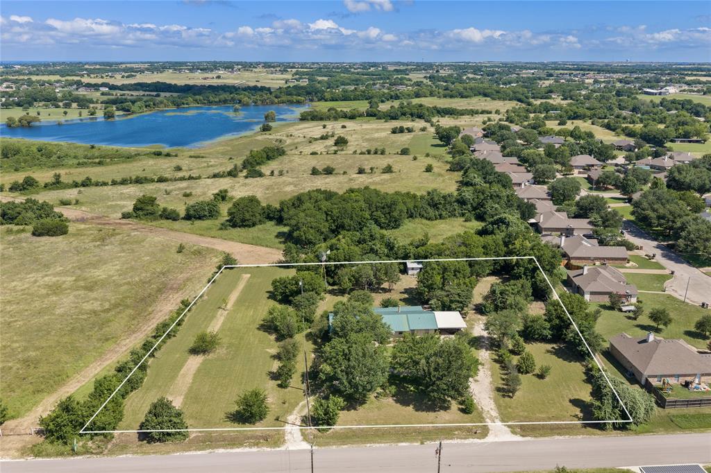 Expansive property featuring a large land parcel outlined in white, established trees, and a visible structure with a green metal roof