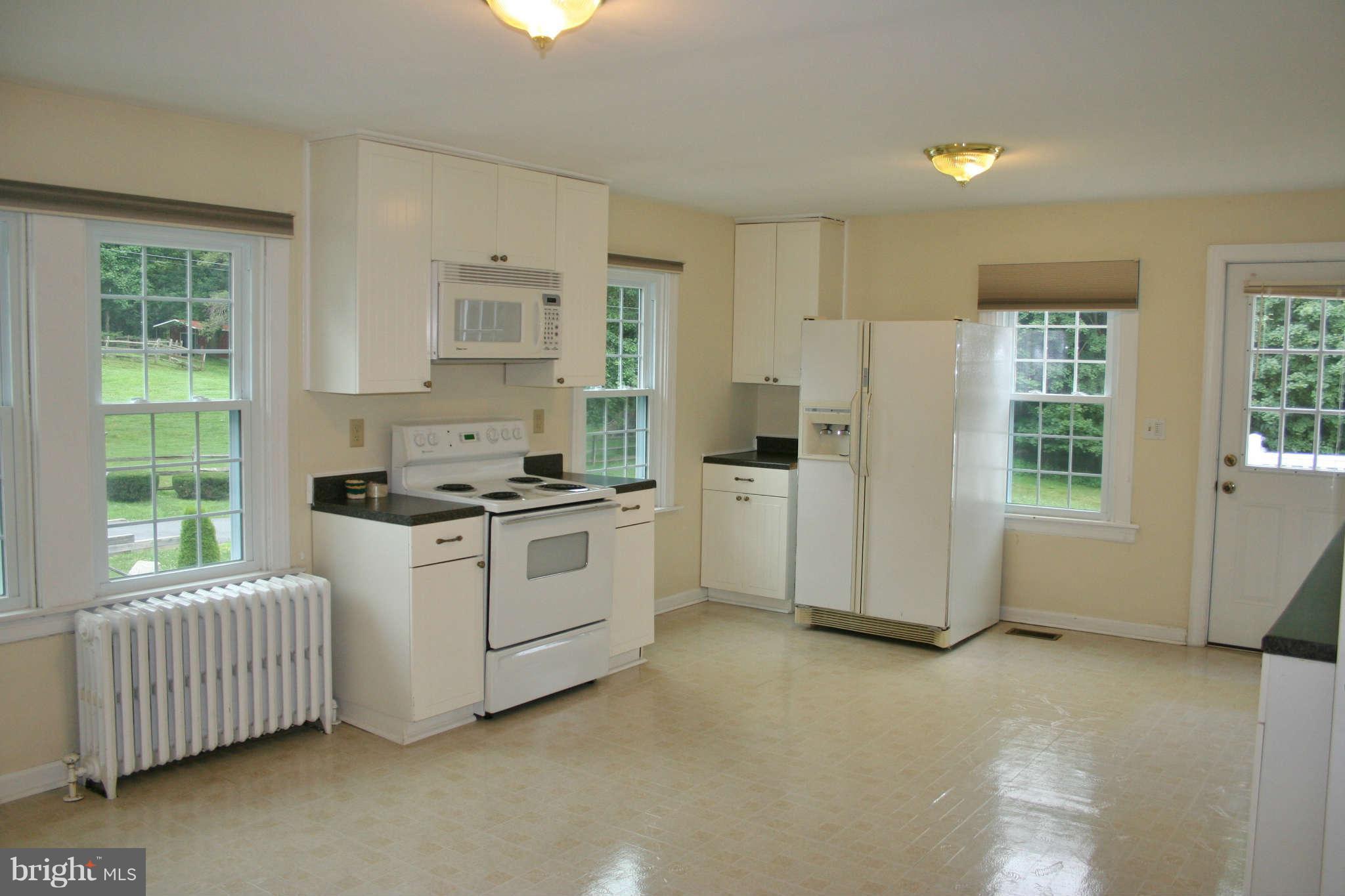 10529 Old Court Road Woodstock, MD 21163 - Photo 11 of 26 a kitchen with white cabinets and white appliances