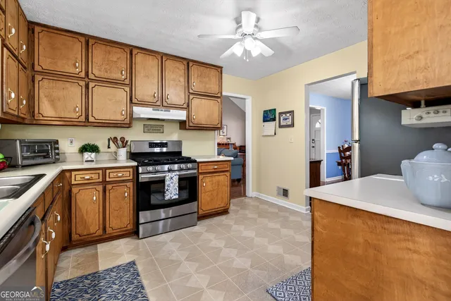 a kitchen with stainless steel appliances granite countertop a sink and a stove next to a window